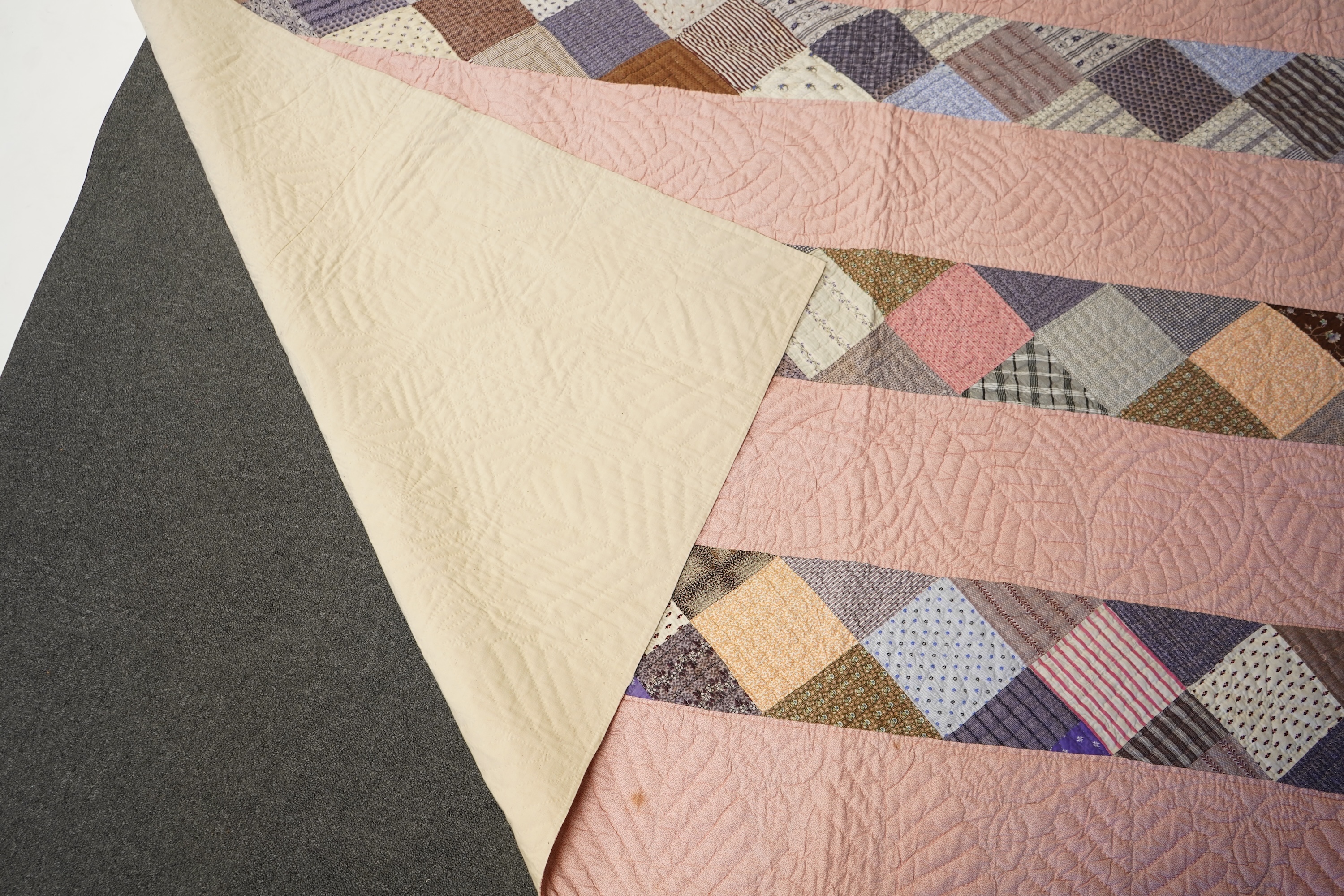 A late 19th century English, possibly ‘North Country’ cotton, hand quilted bed cover. Worked in stripes, with alternate patch worked stripes of differing colour fabrics. Made from fashionable cotton fabrics of the era. R